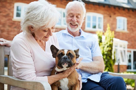 Man and woman holding their dog while sitting on a bench